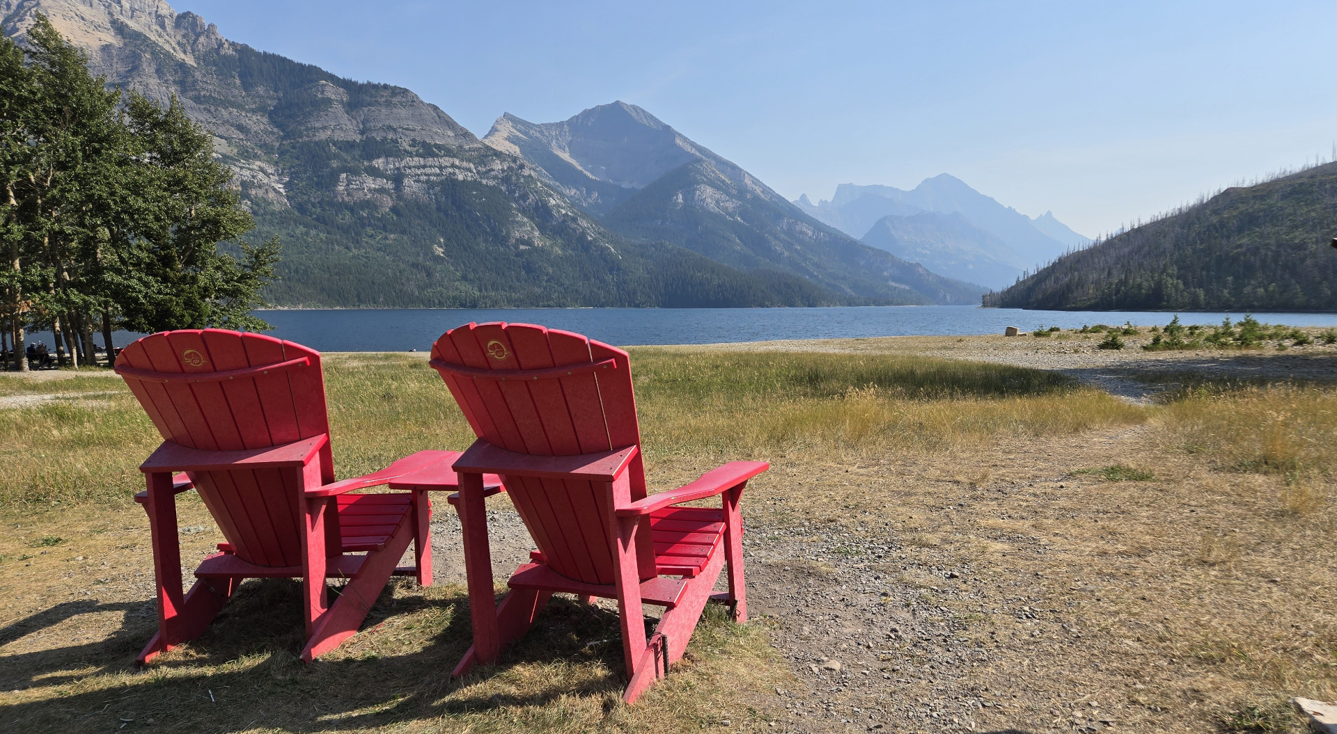 Red Adirondack chairs overlooking a mountain lake in the Alberta Rockies