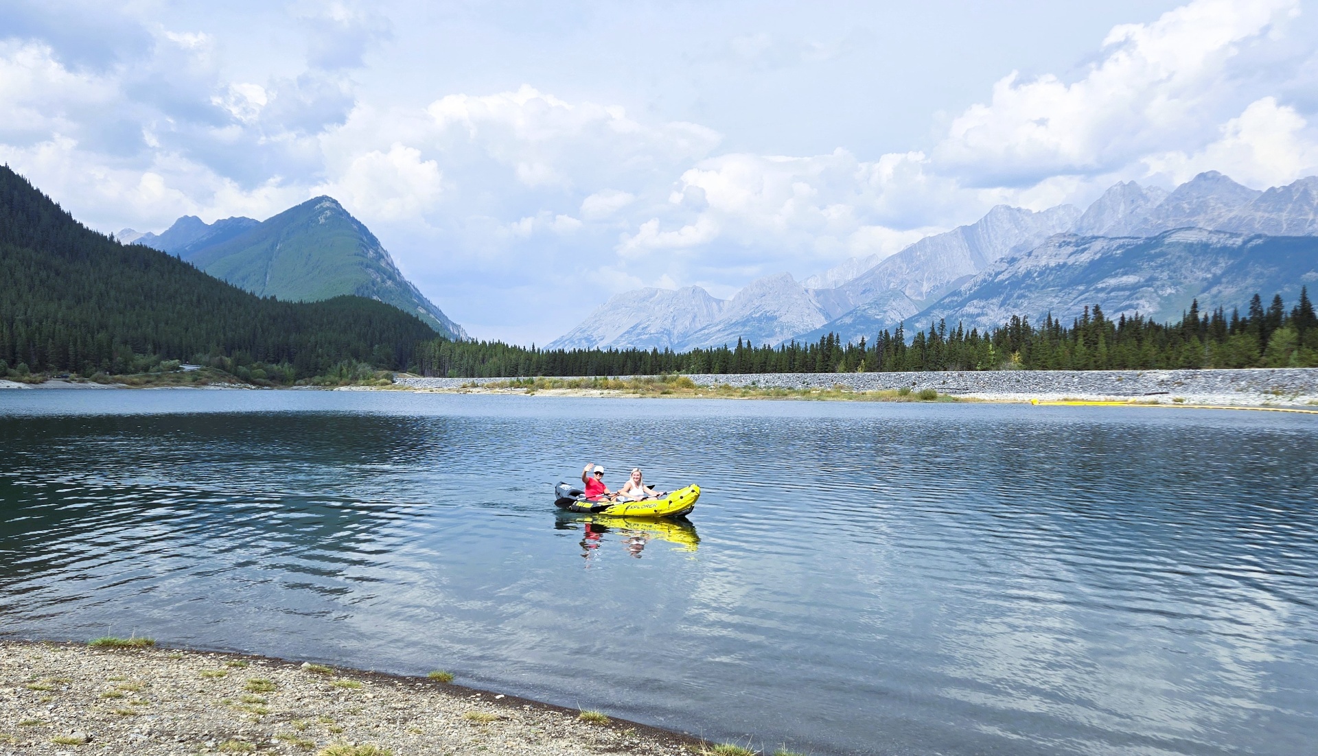 Two people kayaking on a calm mountain lake in the Alberta Rockies